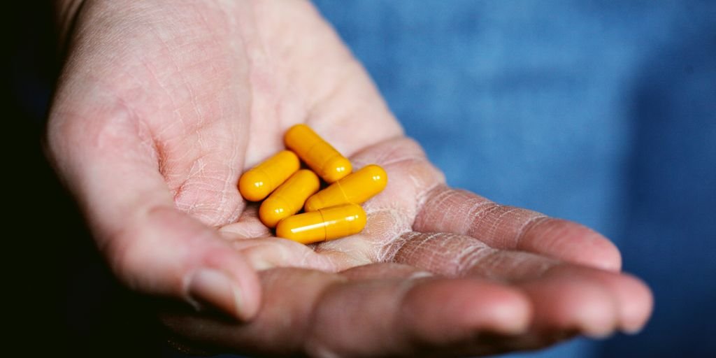 yellow medication pill on persons hand