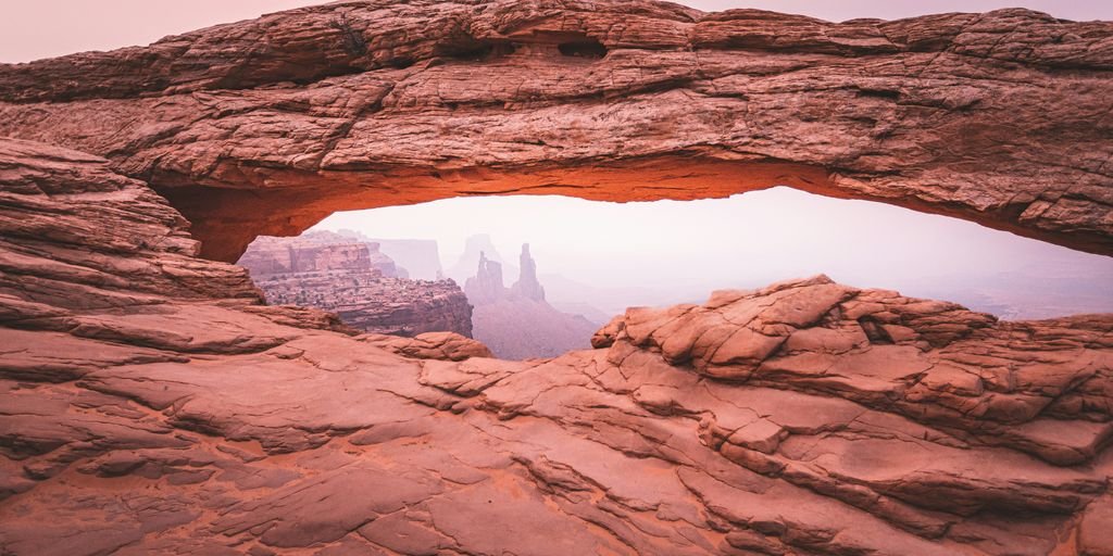 person in black jacket standing on brown rock formation during daytime