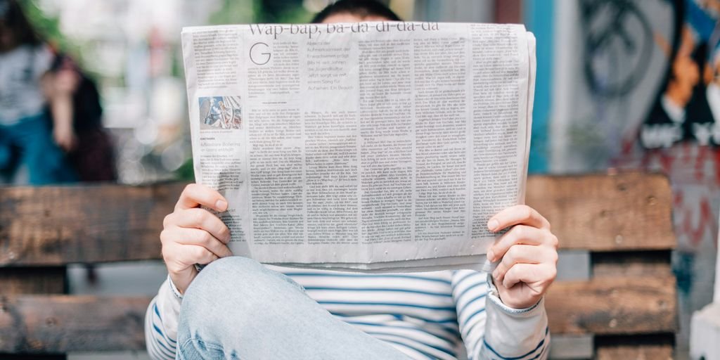 man sitting on bench reading newspaper