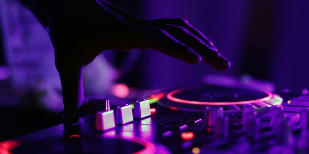 selective focus silhouette photography of man playing red-lighted DJ terminal