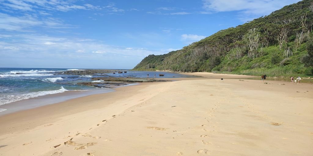 A sandy beach next to the ocean under a blue sky